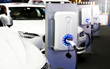 A row of white cars plugged into electric vehicle charging stations