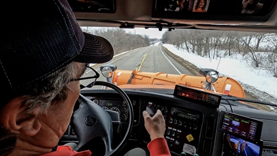 View of a driver, assist-system, and road from inside a snowplow