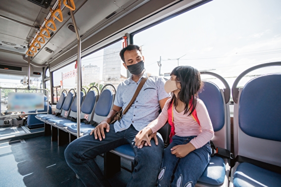Masked parent and child sitting on a public transit vehicle