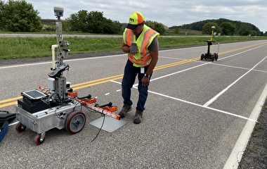 Researcher looking down at a pavement measuring robot