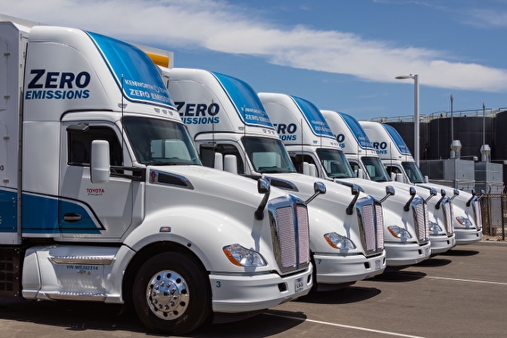 Five zero emissions semi trucks parked in a row