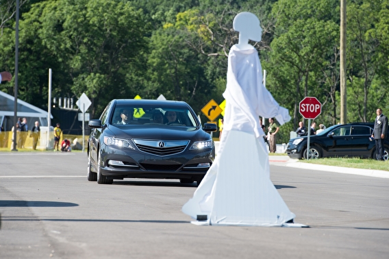 A vehicle approaches a pedestrian dummy in the middle of a road