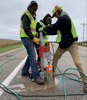 Researchers collecting an asphalt core in the field